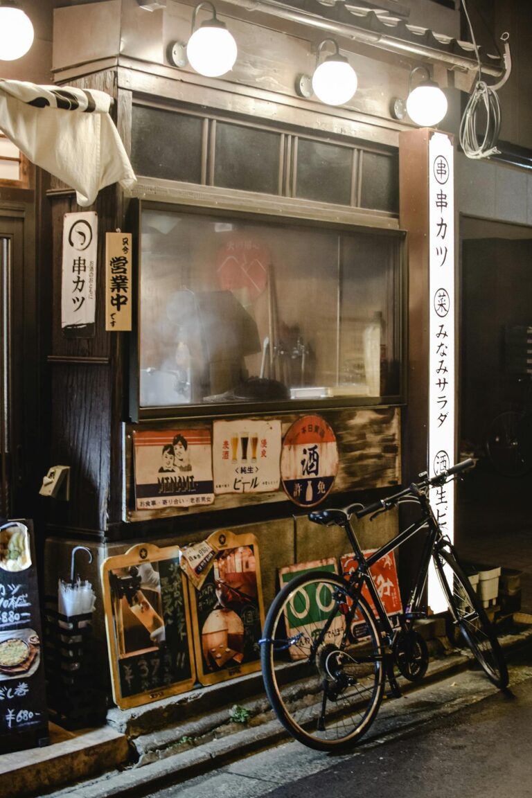 Bicycle parked outside a Kyoto street restaurant at night with vibrant signage and warm lighting.