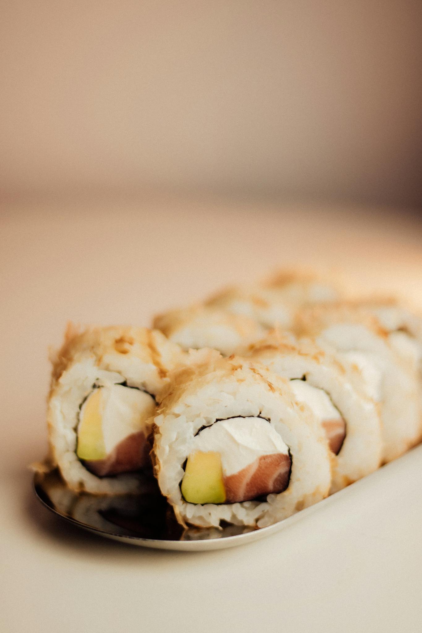 Delicious sushi rolls with salmon, avocado, and cream cheese on a plate.