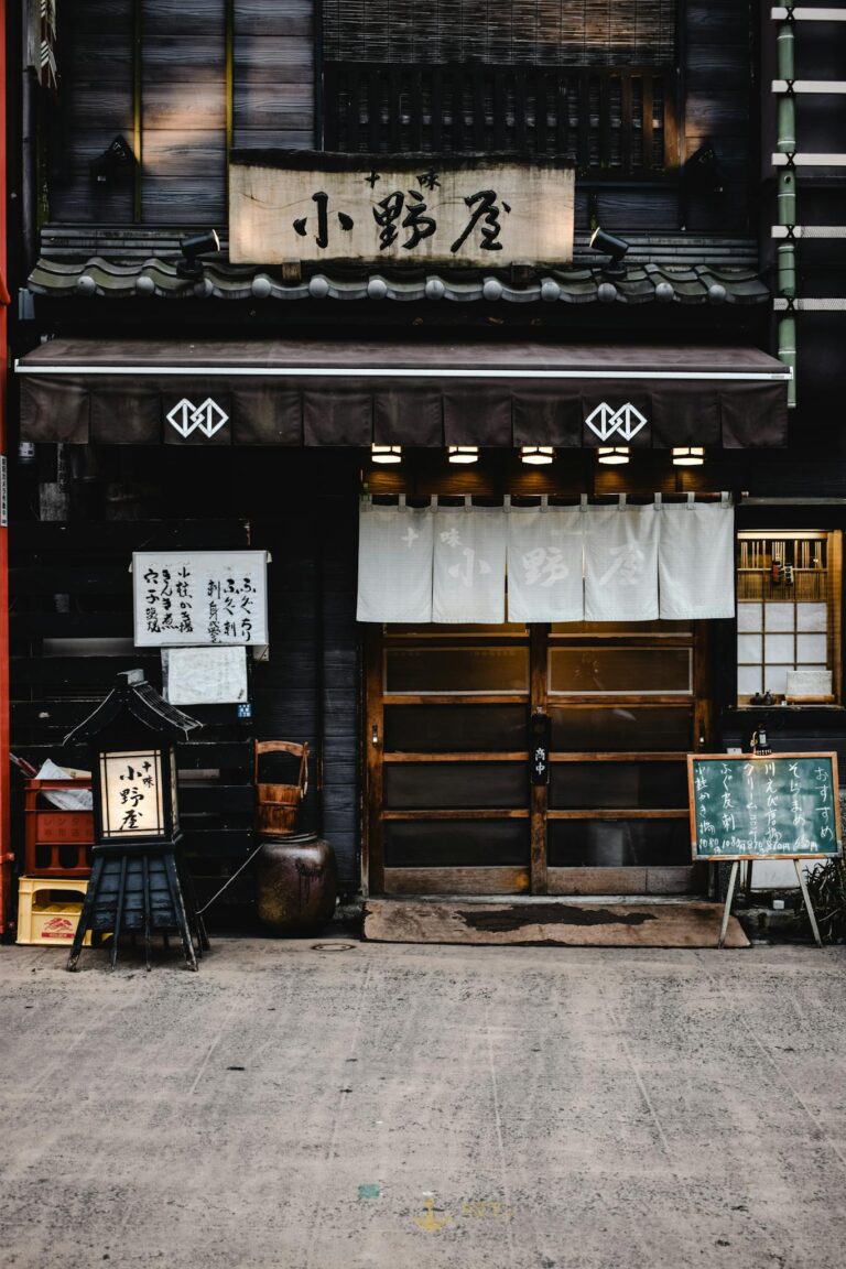 Entrance of a traditional Japanese izakaya with wooden signboards and decorative elements.