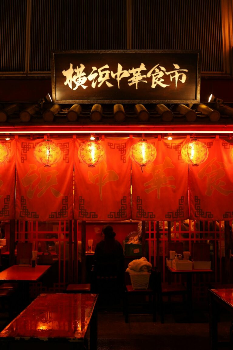 Illuminated Asian food market stall at night with glowing lanterns and signage.
