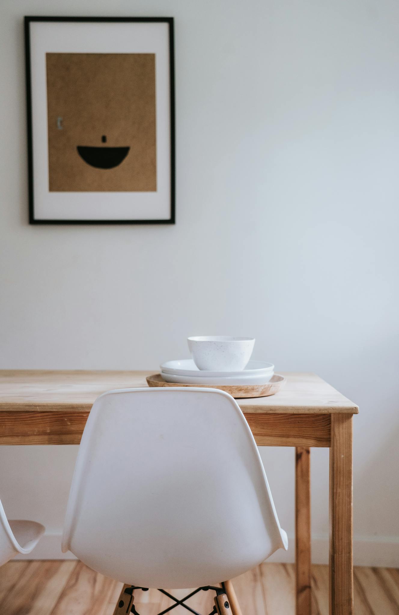Minimalist Japandi style dining area with ceramics and framed art piece.