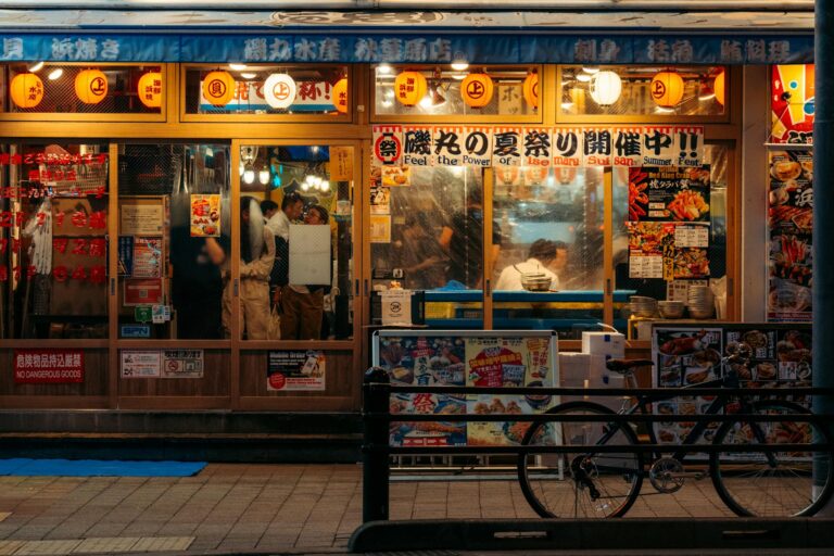 Vibrant scene of a bustling Japanese restaurant with glowing lanterns at night.